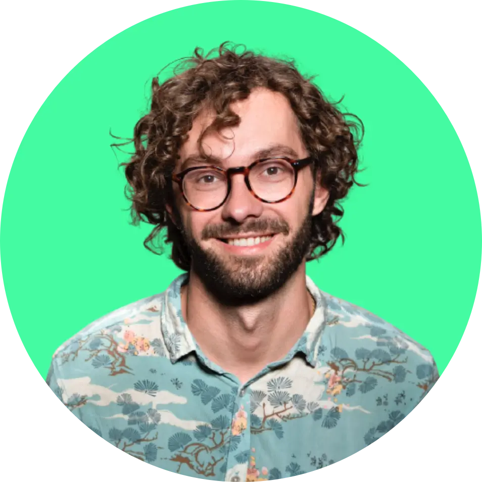 A man with curly hair and glasses smiling against a green circular background with a glitch effect at the bottom.